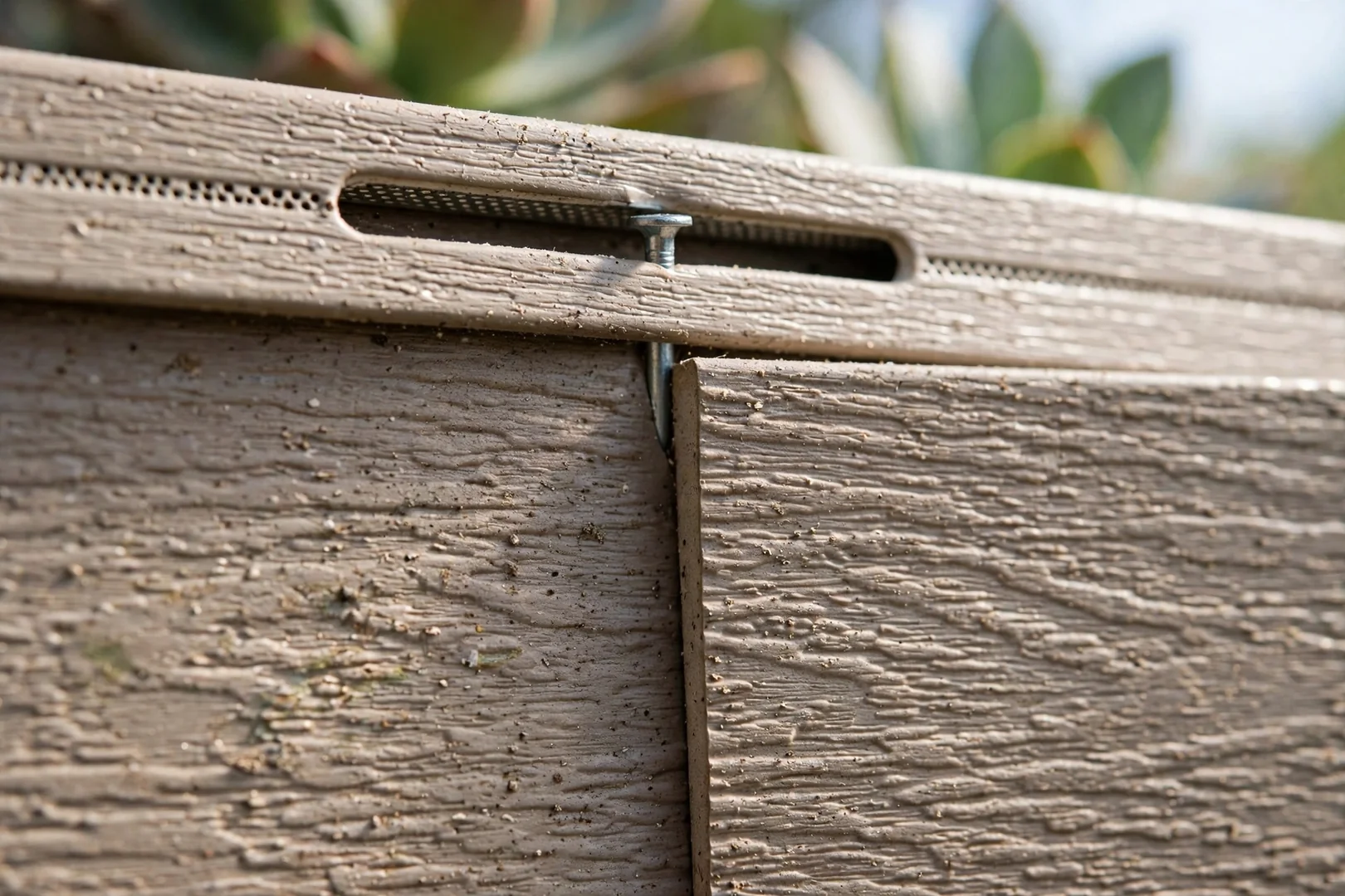 Close-up of interlocked vinyl siding butt joint and center-slotted nailing hem detail